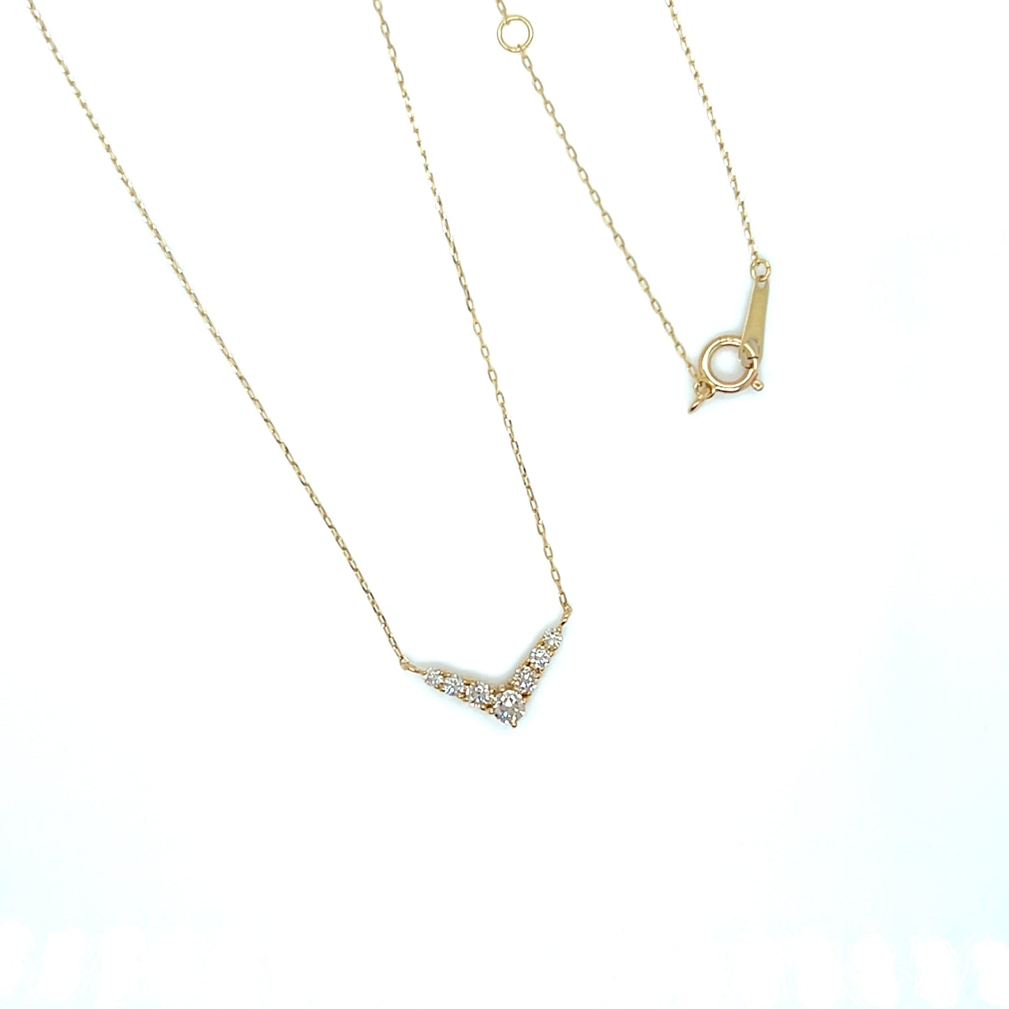 V shape Gold necklace with a small pendant on a white background