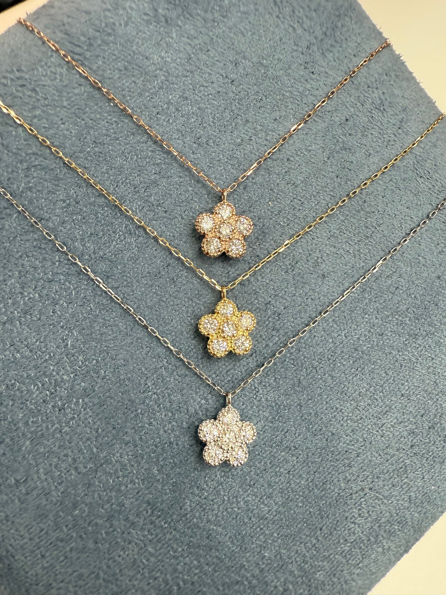 Gold necklace with flower-shaped pendants on a textured gray surface