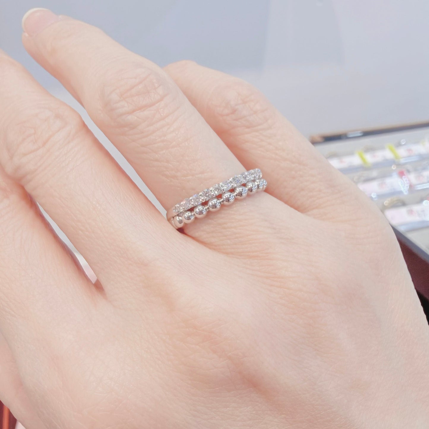Hand wearing a silver ring with a blurred background