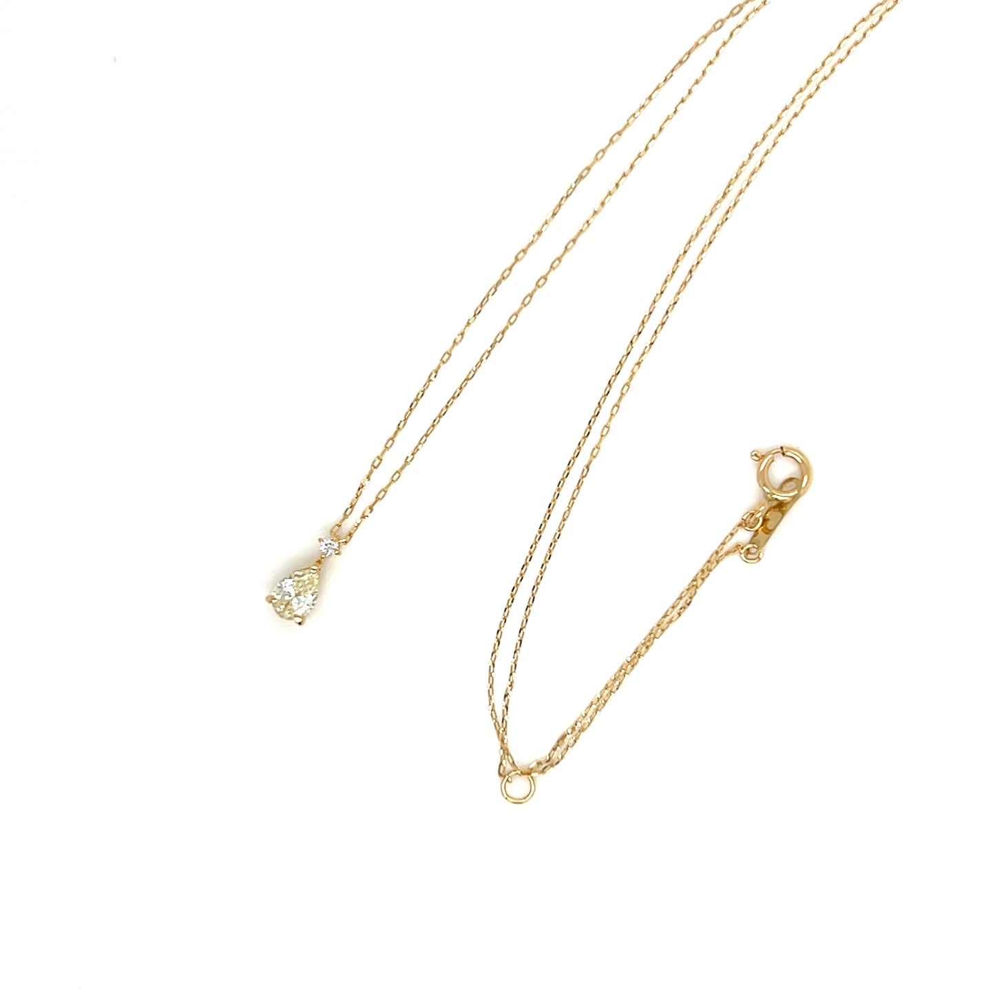 Pear shaped diamond gold necklace with a small pendant on a white background