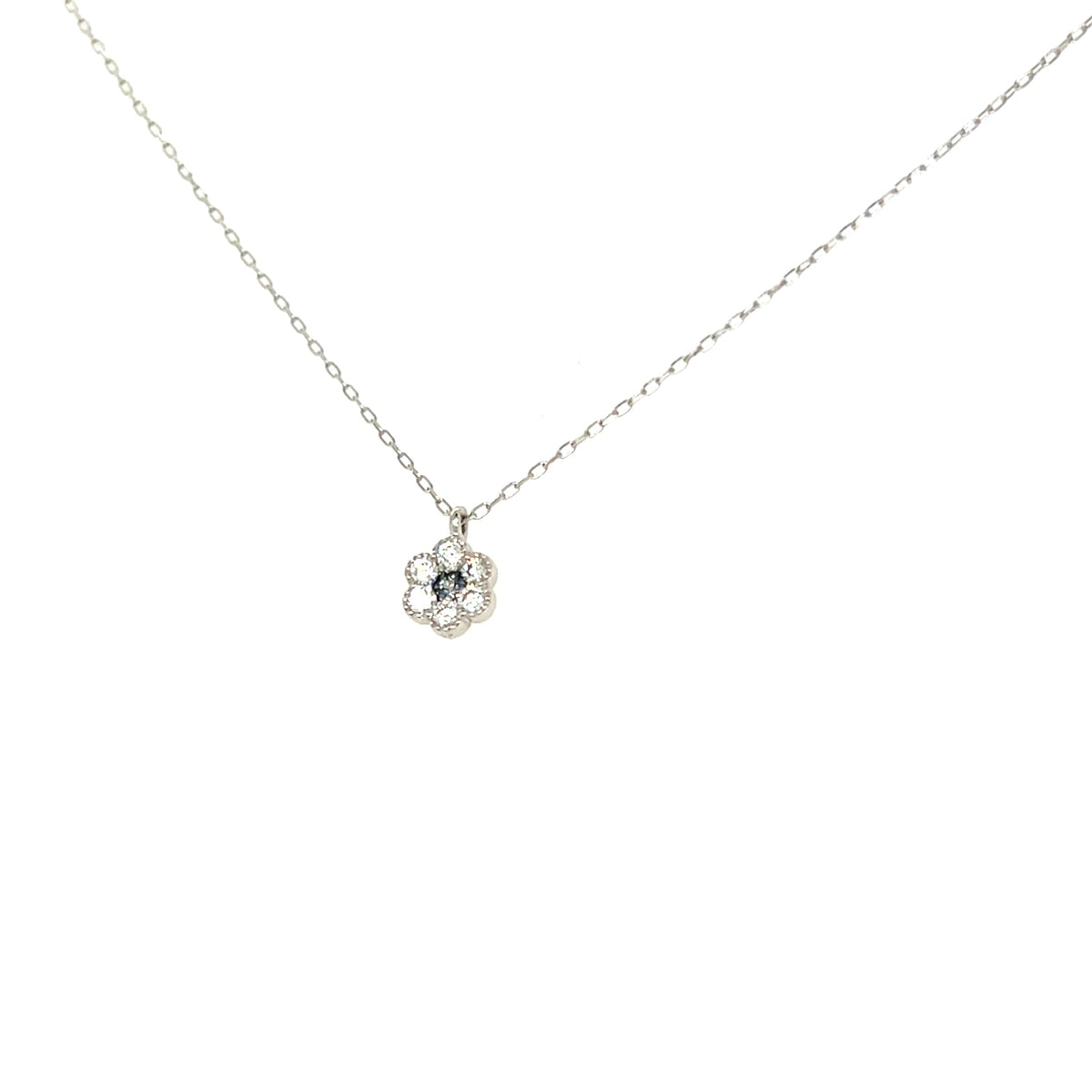 A delicate silver chain necklace with a small flower-shaped pendant featuring a dark blue center stone surrounded by clear stones, shown against a plain white background.