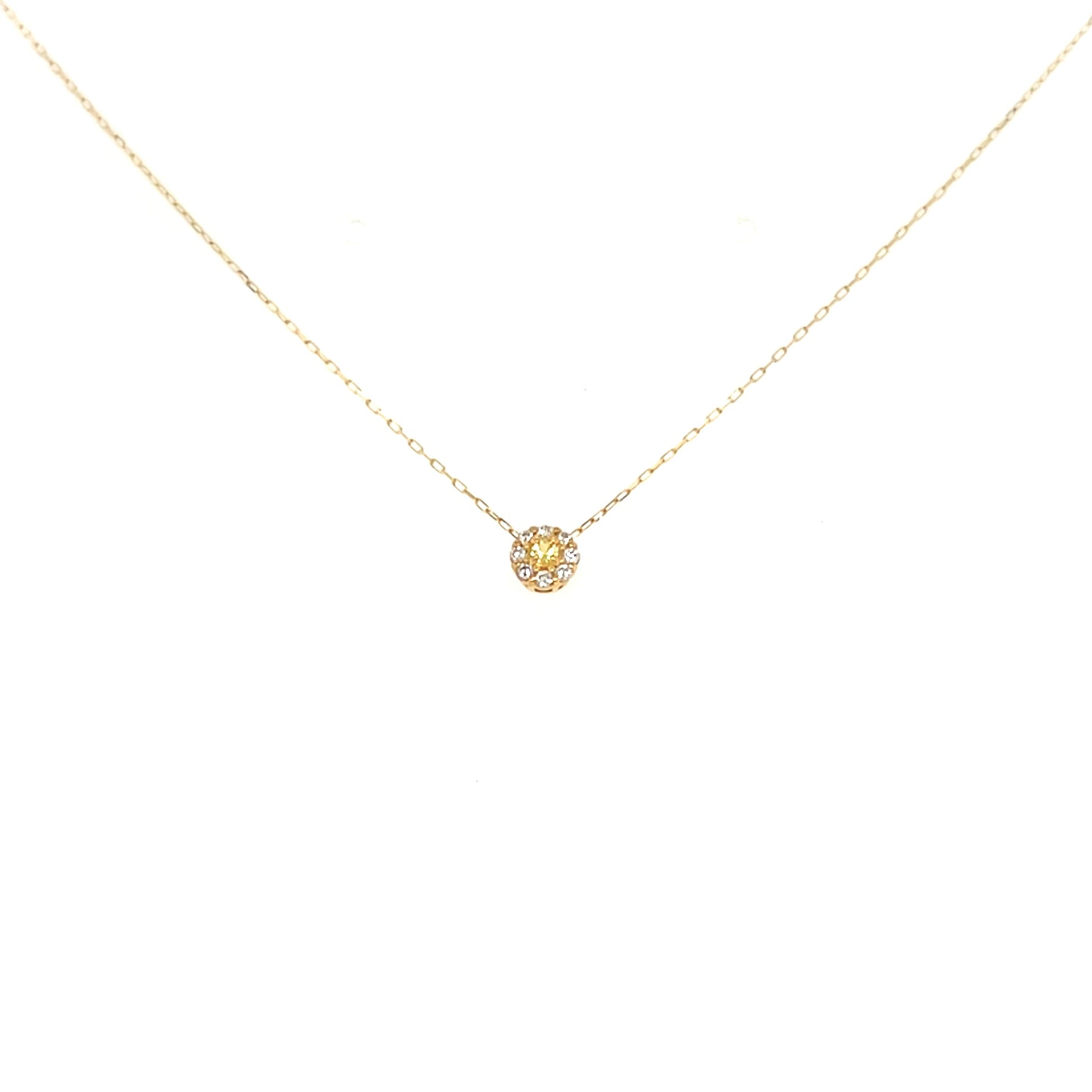 Gold necklace with a small round pendant on a white background