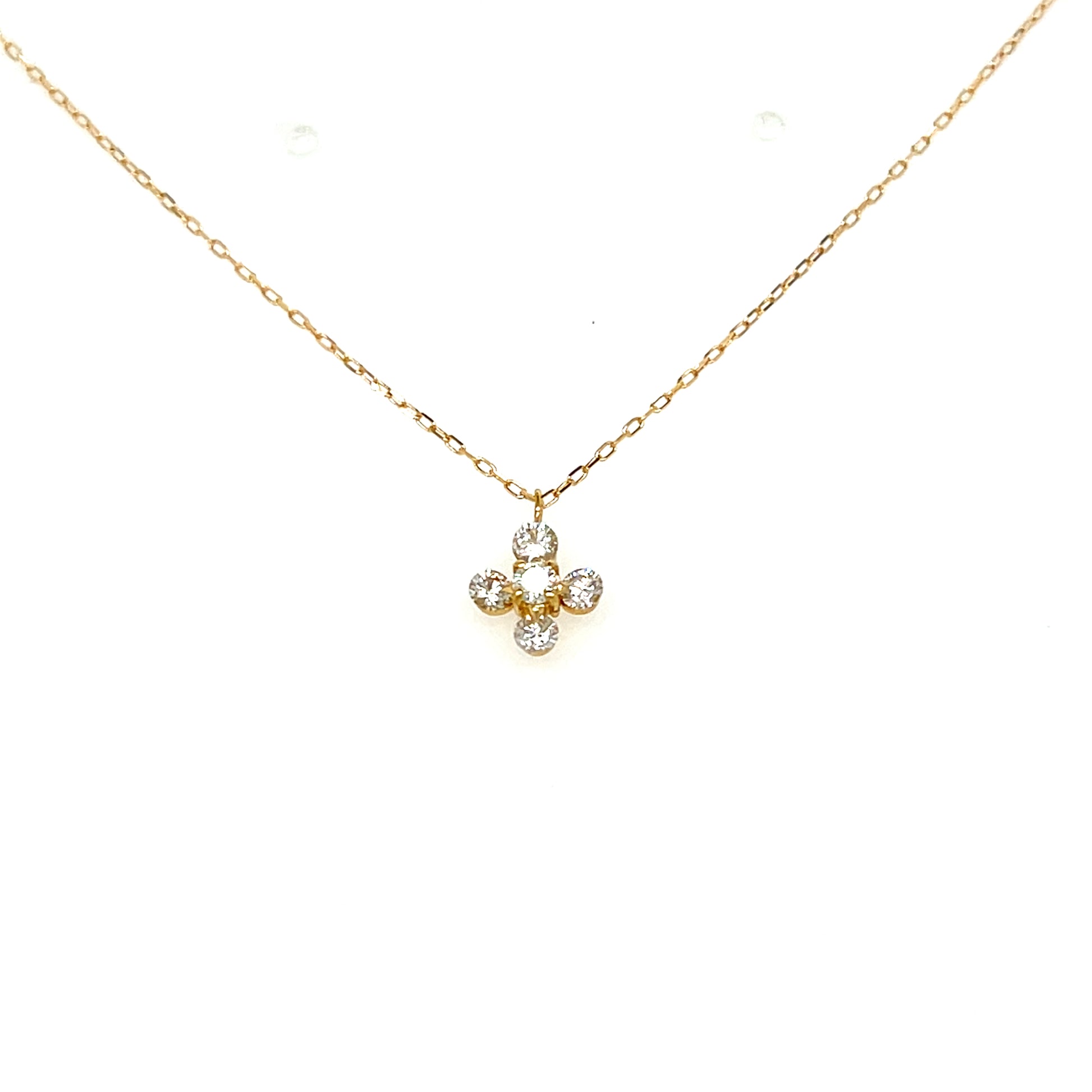 A delicate gold chain necklace with a small four-petal flower pendant set with clear round gemstones, displayed against a solid white background.