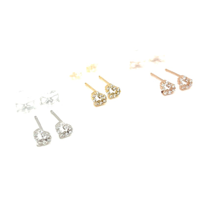 Three pairs of heart-shaped stud earrings on a plain white background, shown in silver, yellow gold, and rose gold tones. Each pair features a heart-shaped setting with small clear stones and a butterfly back.