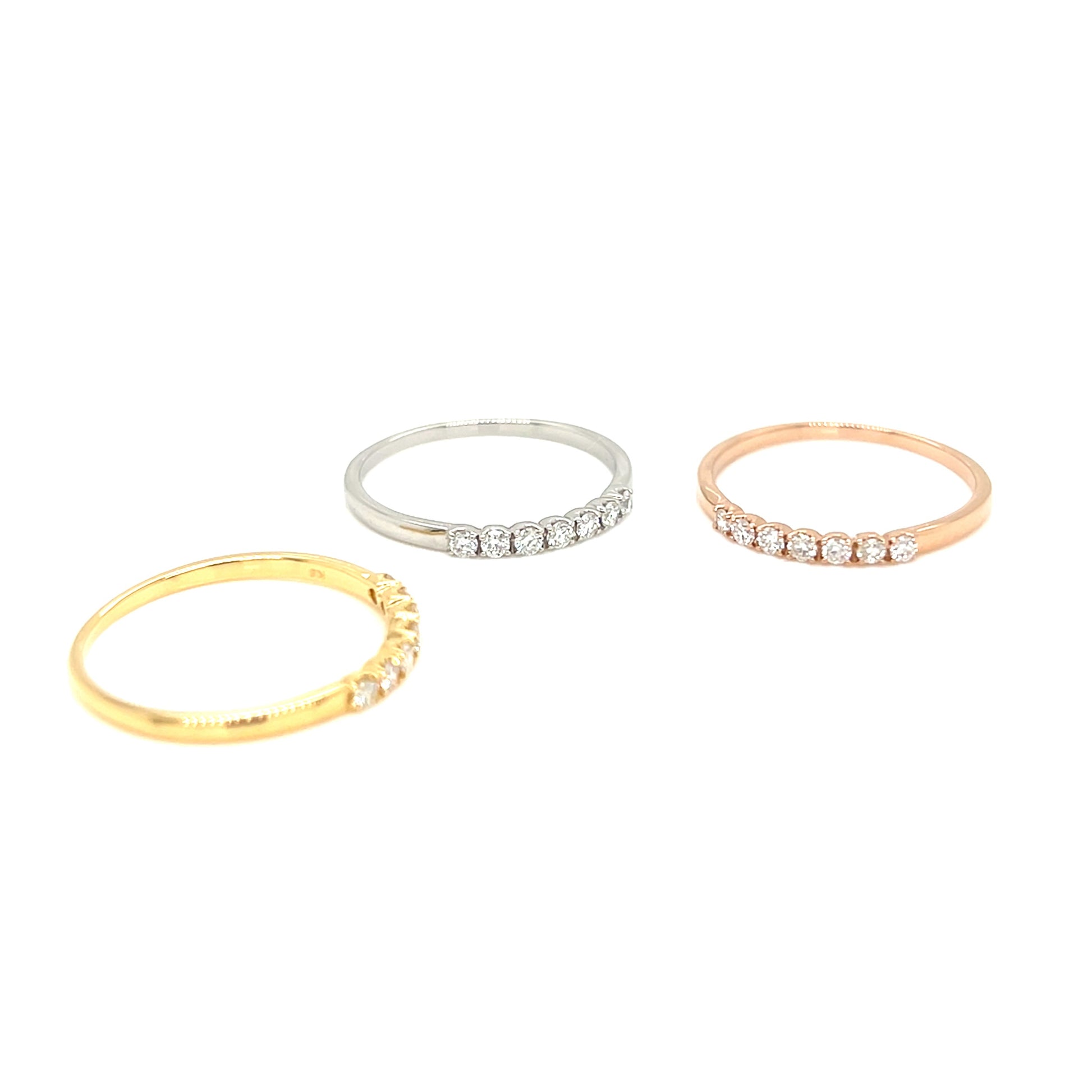 Three slim pave rings in yellow gold, silver, and rose gold, each set with small clear stones, displayed on a clean white background.