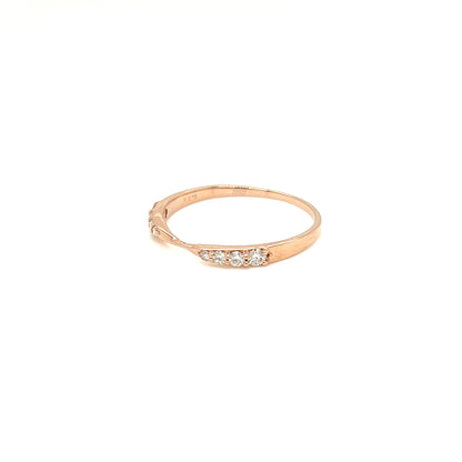 A delicate rose gold ring with a row of small clear gemstones on the front, photographed against a solid white background.