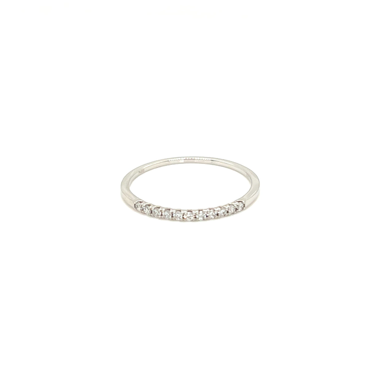 A thin silver band ring featuring a row of small clear gemstones set along the front half, photographed against a solid white background.