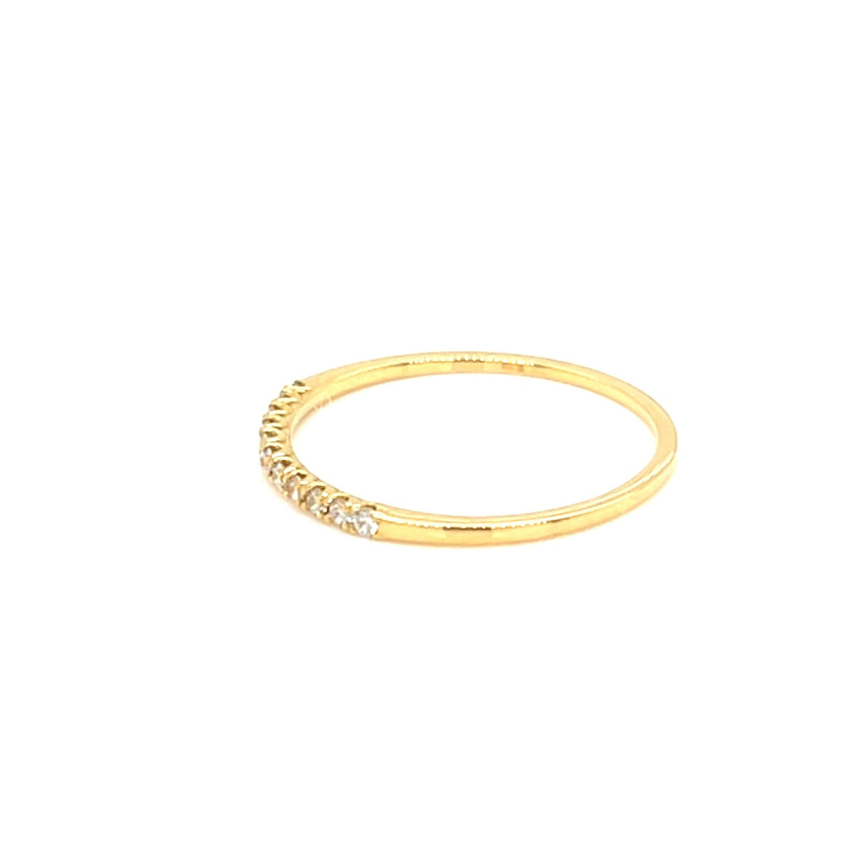 A delicate yellow gold band ring featuring a row of small, clear pavé-set stones along the front, shown against a solid white background.