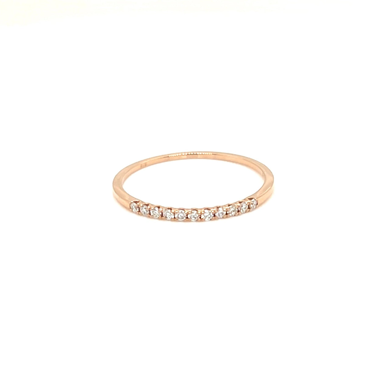 A delicate rose gold eternity ring with a row of small clear stones, centered on a solid white background.
