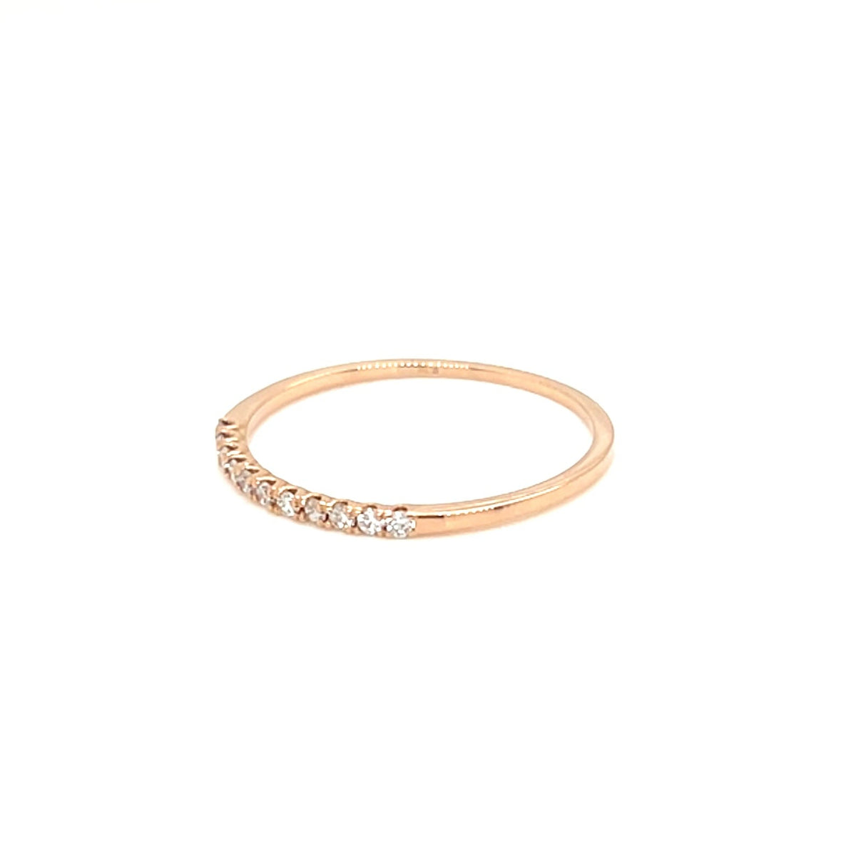 A delicate rose gold ring featuring a row of small clear stones along the front, displayed against a solid white background.
