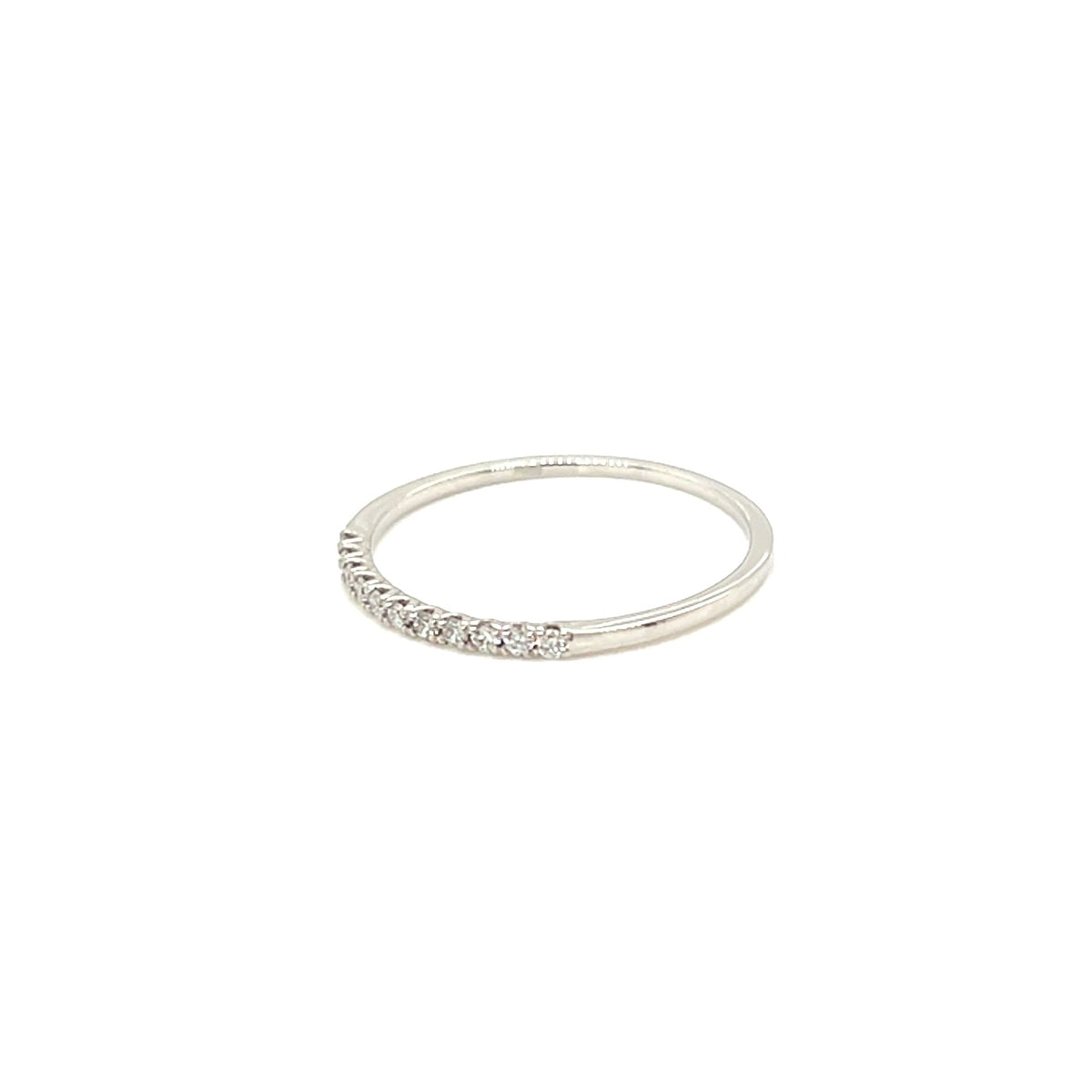 A thin silver band ring featuring a row of small clear stones along the front, photographed against a solid white background.
