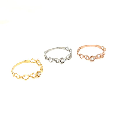 Three delicate heart-link rings in yellow gold, silver, and rose gold, arranged on a plain white background.
