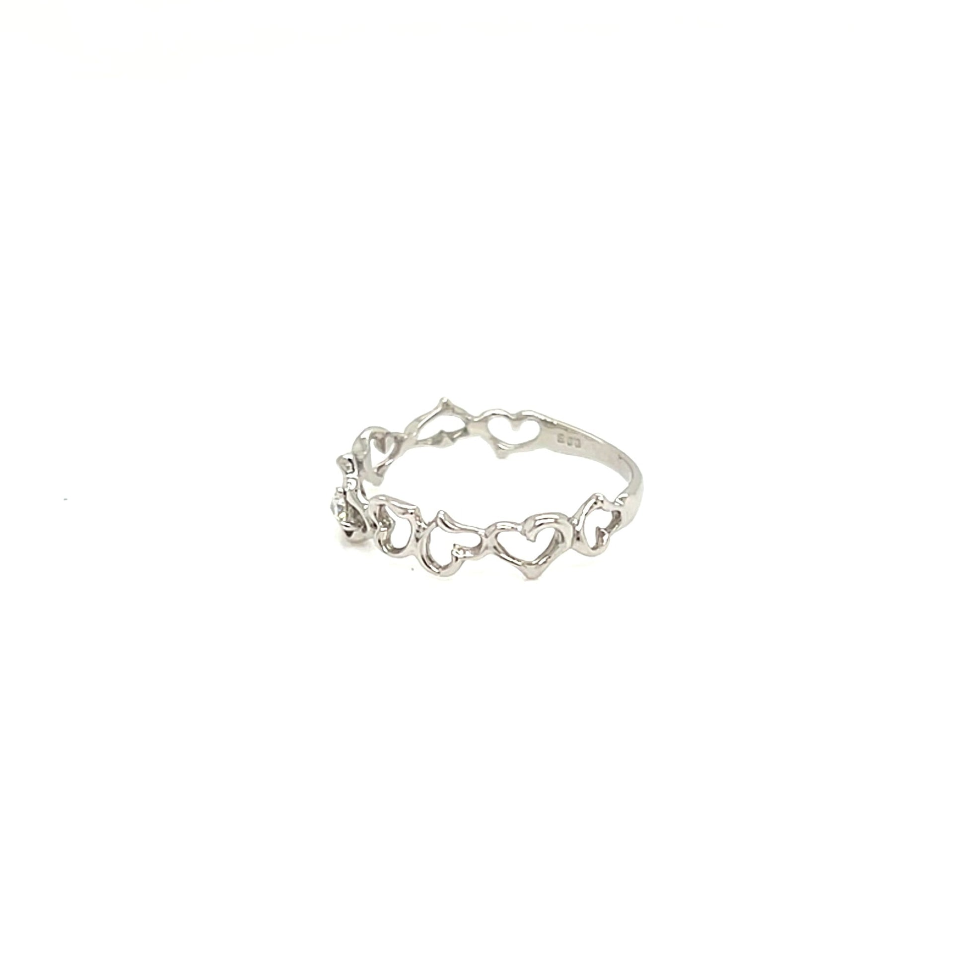 A delicate silver ring featuring a continuous chain of small open heart links, photographed on a solid white background.