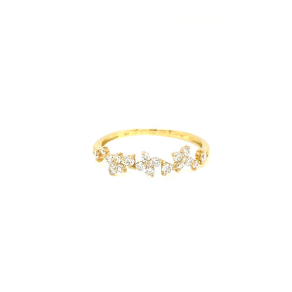 A delicate yellow gold ring featuring a row of small, clear floral cluster stones set across the front, displayed on a solid white background.