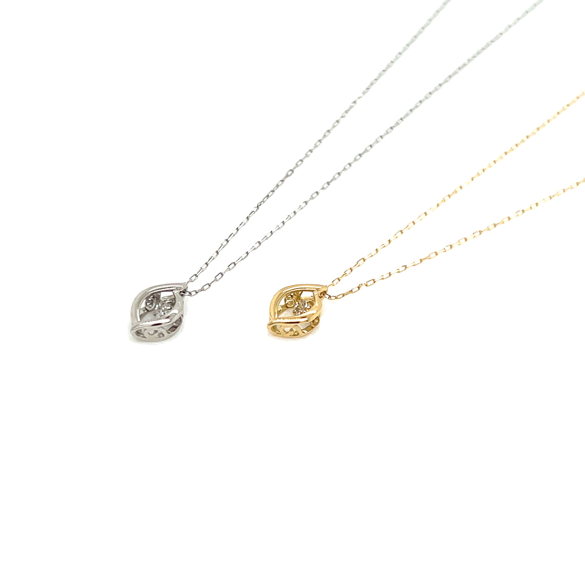 Two delicate leaf-shaped pendant necklaces on fine chains, one in silver and one in yellow gold, both set with small clear stones, displayed on a clean white background.