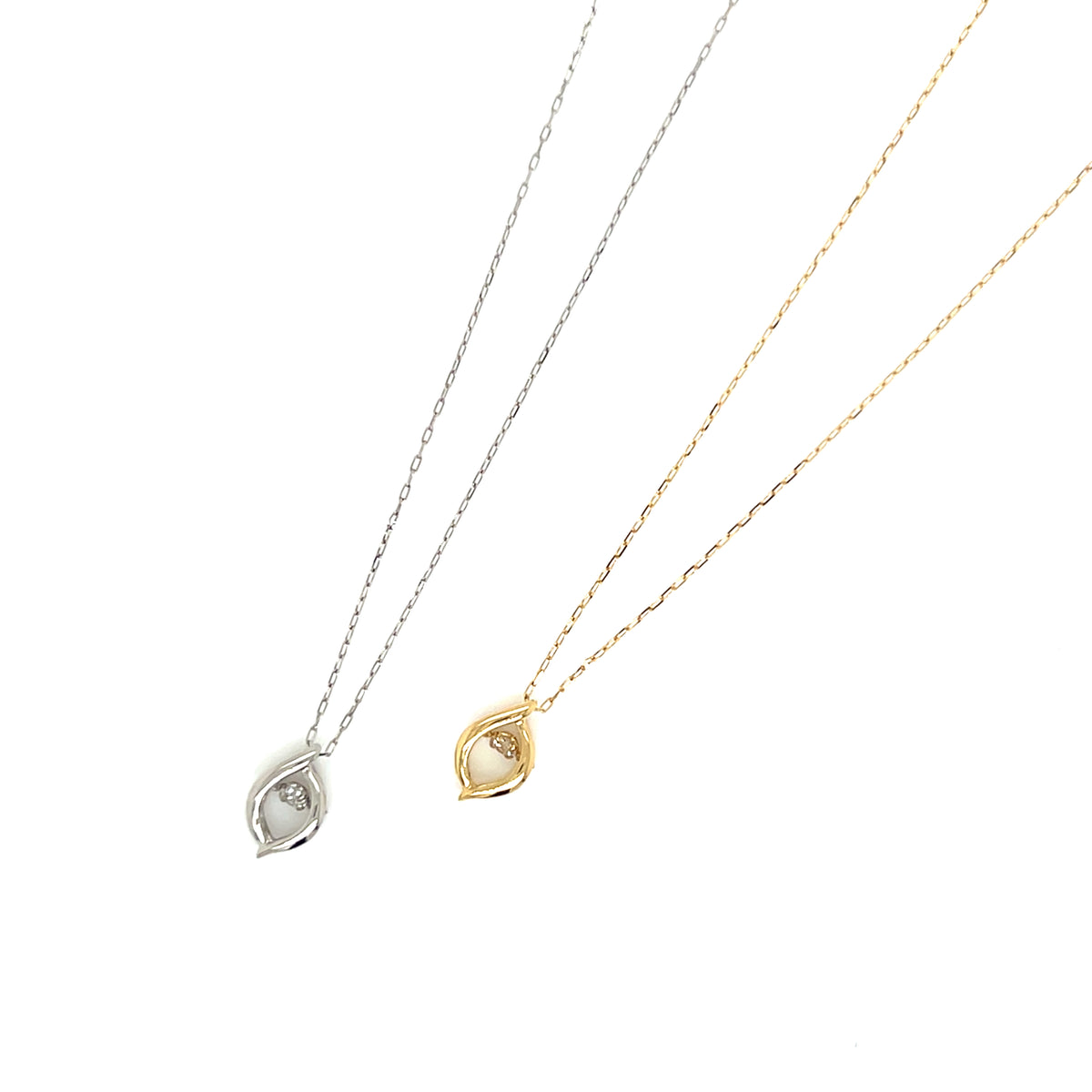 Two delicate teardrop-shaped pendant necklaces on a plain white background, one in silver and one in yellow gold, both featuring a small clear stone in a bezel setting.