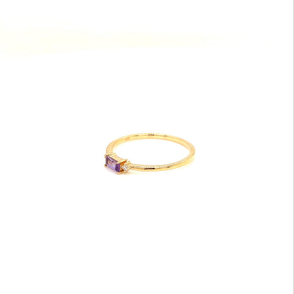 A delicate yellow gold ring featuring a small rectangular purple amethyst gemstone, photographed against a seamless white background.