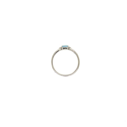 A silver ring featuring a small rectangular light blue gemstone in a bezel setting, centered on a plain white background.