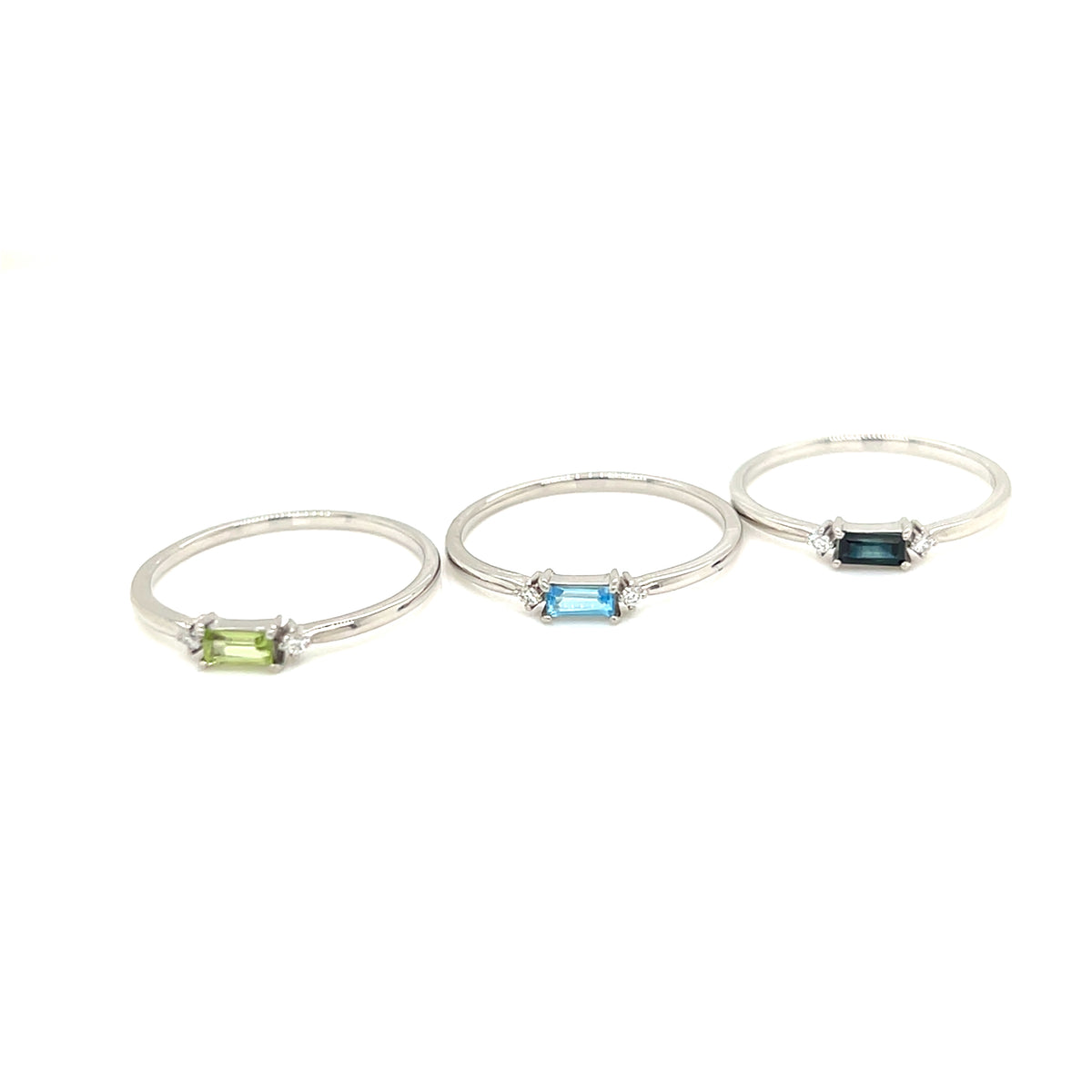 Three silver rings with rectangular gemstones in green, light blue, and dark blue, displayed on a clean white background.
