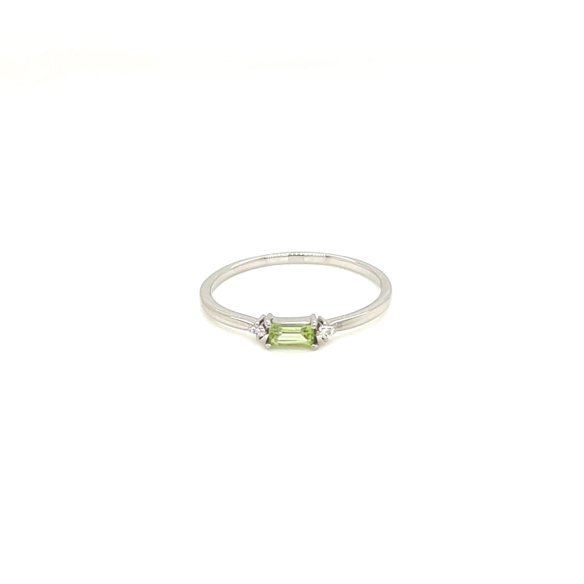 A silver ring featuring a small emerald-cut green gemstone in a prong setting, flanked by two tiny clear accent stones, shown against a plain white background.