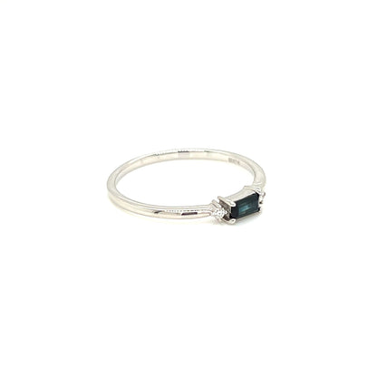 A delicate silver ring featuring a small rectangular dark green gemstone, photographed on a seamless white background.