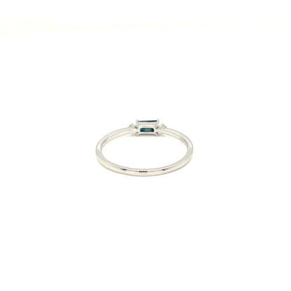 A silver ring featuring a small rectangular emerald-cut blue gemstone in a bezel setting, shown against a plain white background.