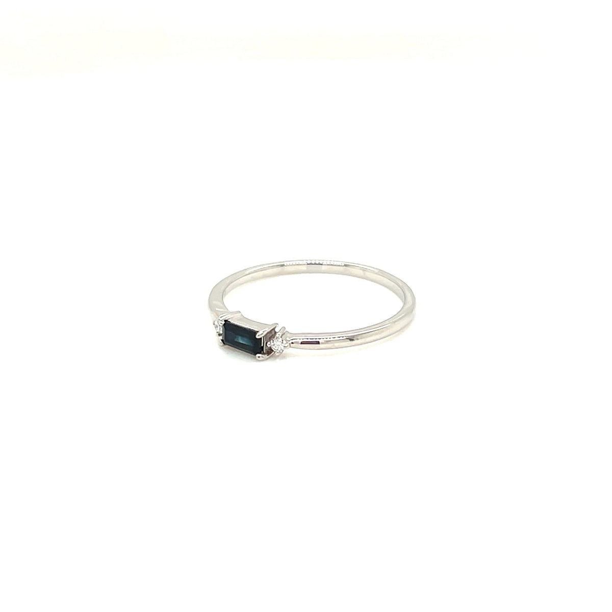 A silver ring featuring a rectangular dark blue sapphire stone and small clear accent stones on a white background.
