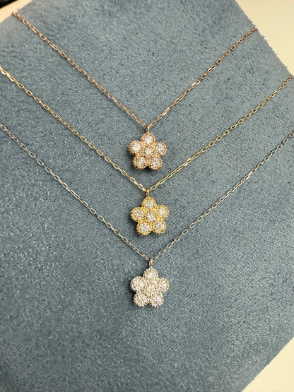 Gold necklace with flower-shaped pendants on a textured gray surface