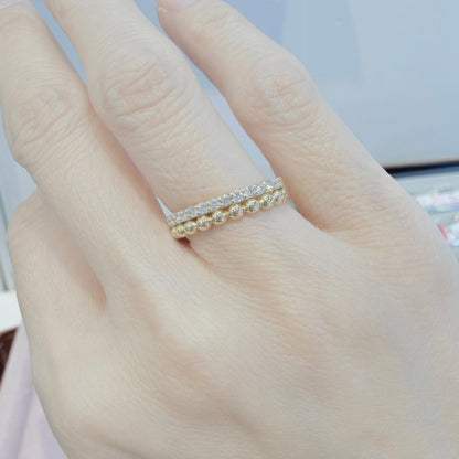 Hand wearing a gold ring with a blurred background
