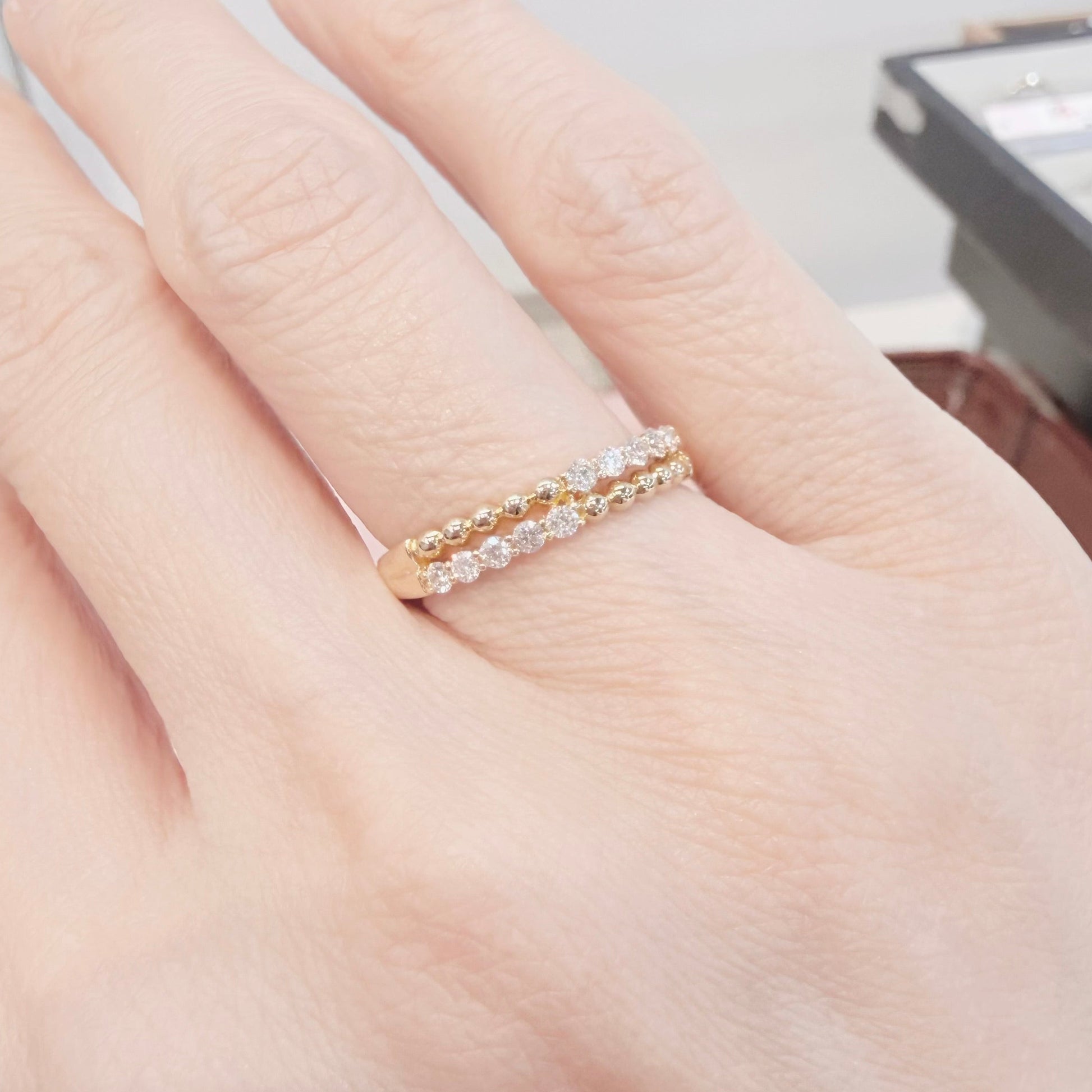 Close-up of a hand wearing a gold and silver ring on a neutral background