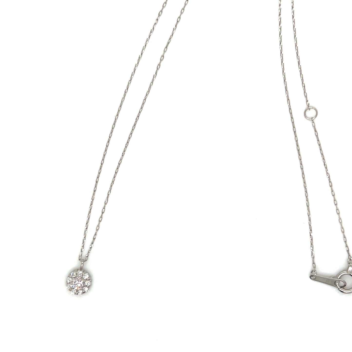 A silver-toned necklace with a delicate chain, featuring a small round pendant paved with clear crystals on the left and a small key-shaped charm on the right, shown against a plain white background.