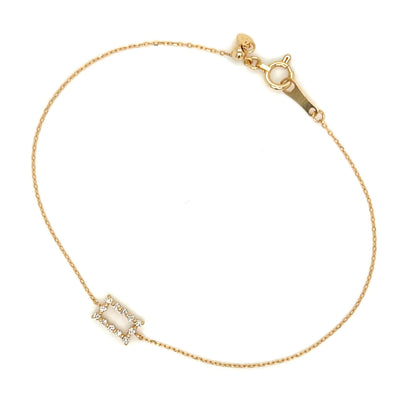 Gold bracelet with a small rectangular diamond on a white background