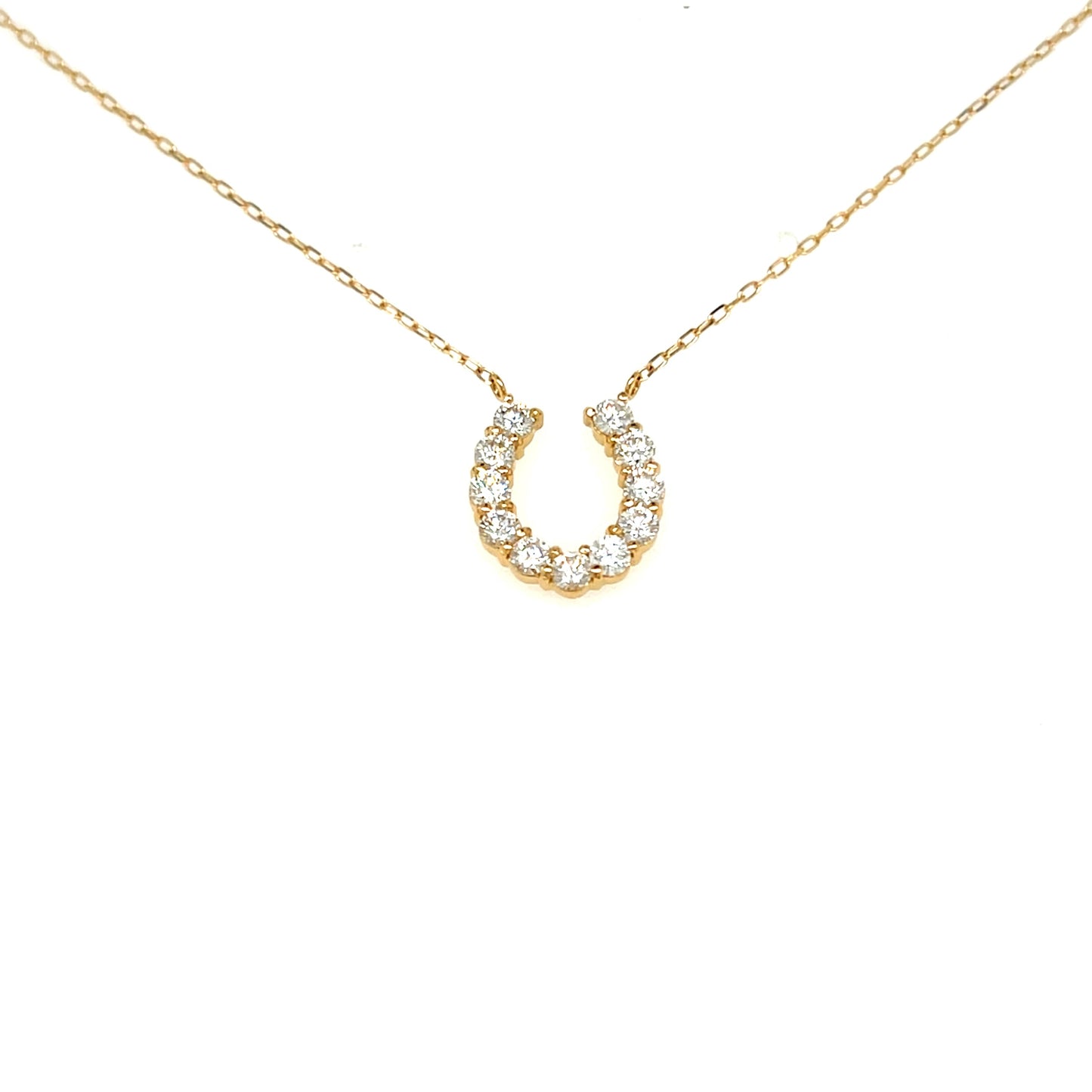 A delicate gold chain necklace featuring a horseshoe-shaped pendant encrusted with small clear stones, displayed against a solid white background.