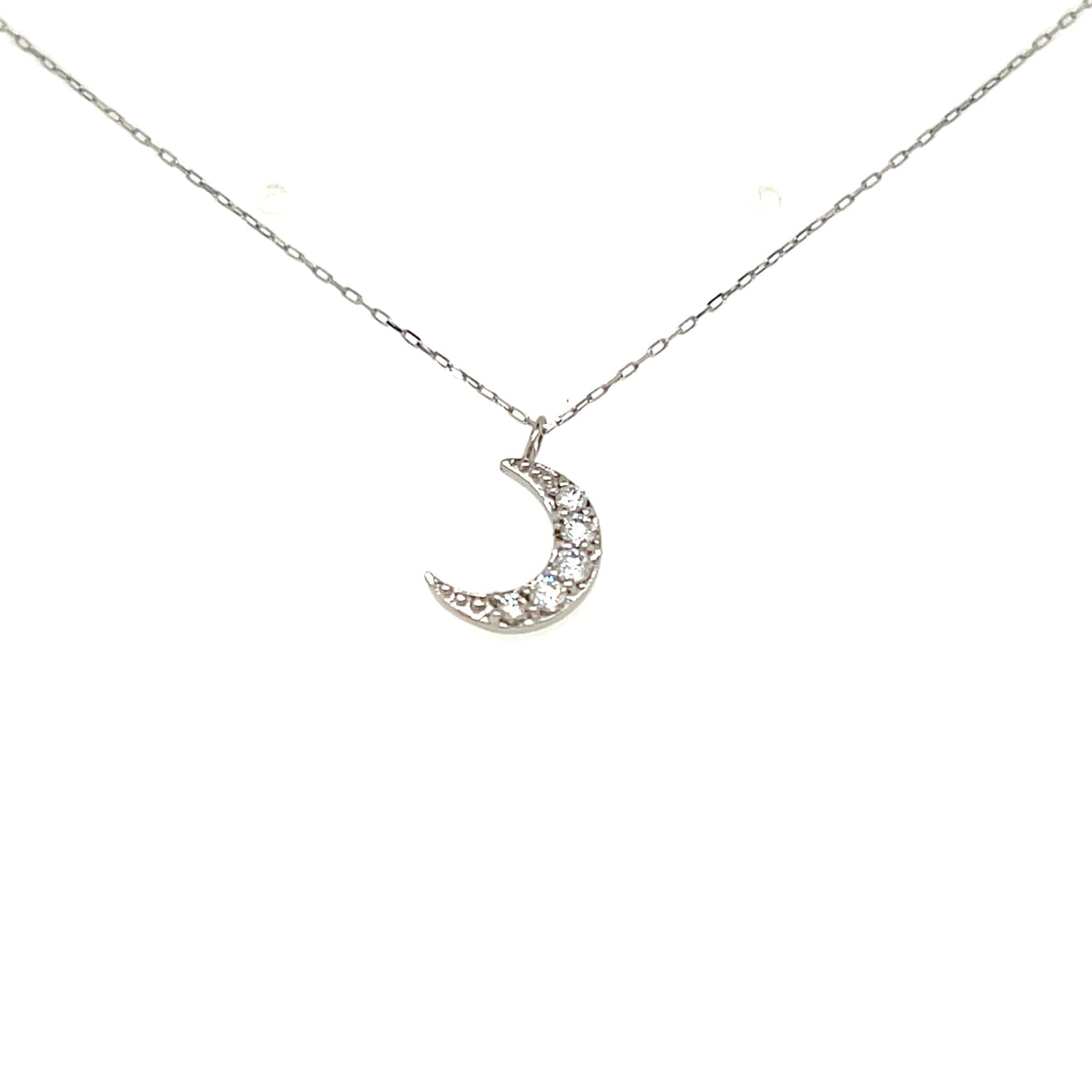 A silver crescent moon pendant necklace adorned with small clear stones, suspended from a delicate silver chain against a plain white background.