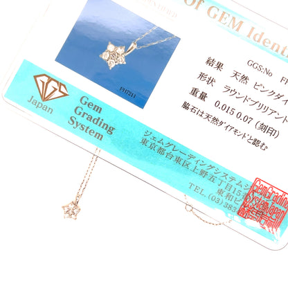 A close-up of a delicate gold-toned pendant necklace with a star and diamond motif, shown draped over its branded Gem Grading System card. The card features a blue inset photo of the necklace, Japanese text, a diamond icon, and a red stamp.
