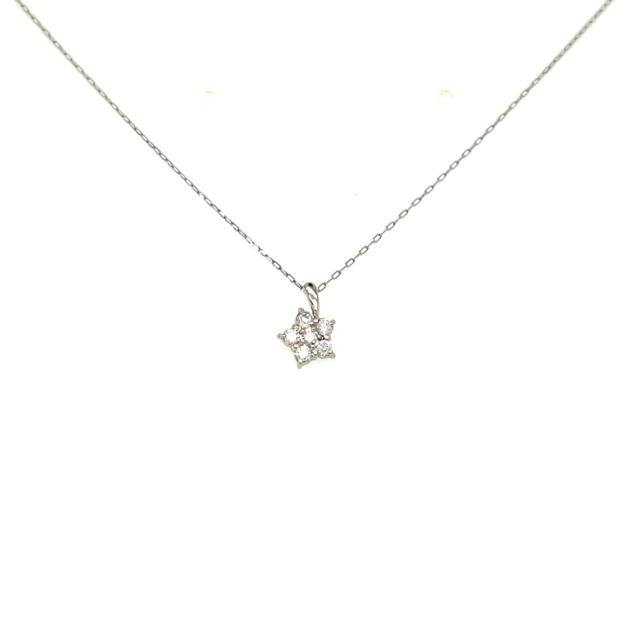 A delicate silver chain necklace with a small pendant featuring tiny clear gemstones, displayed against a solid white background.