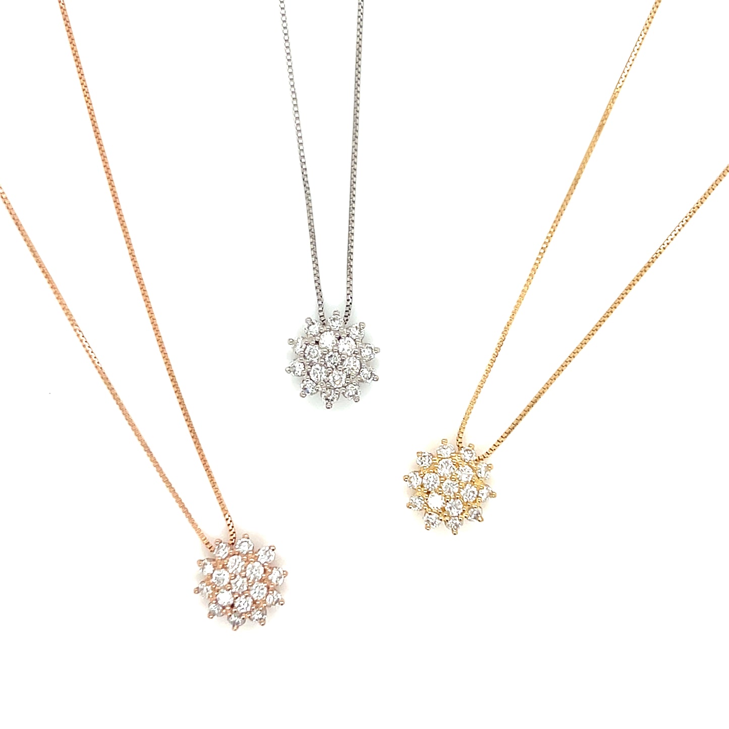 Three snowflake-shaped pendants on necklaces in rose gold, silver, and gold on a white background.