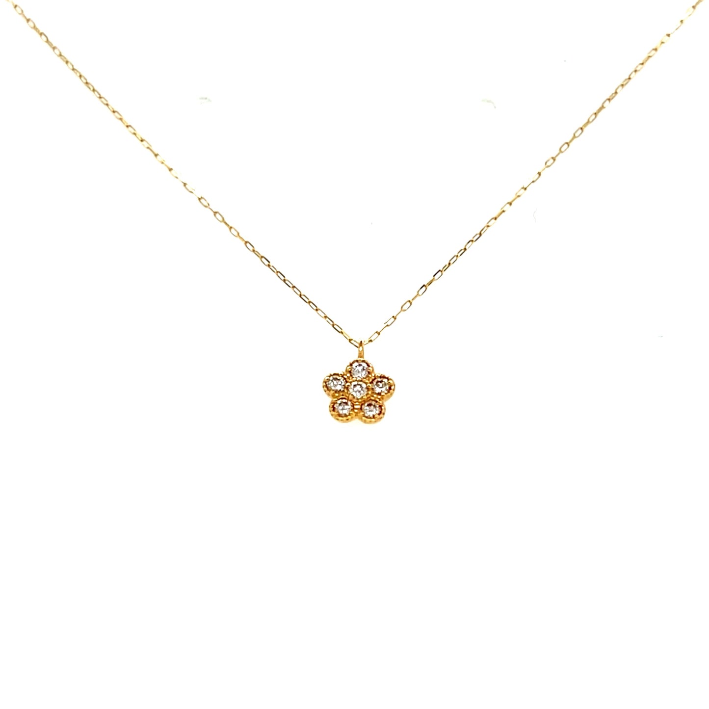 Gold necklace with a small diamond flower pendant on a white background