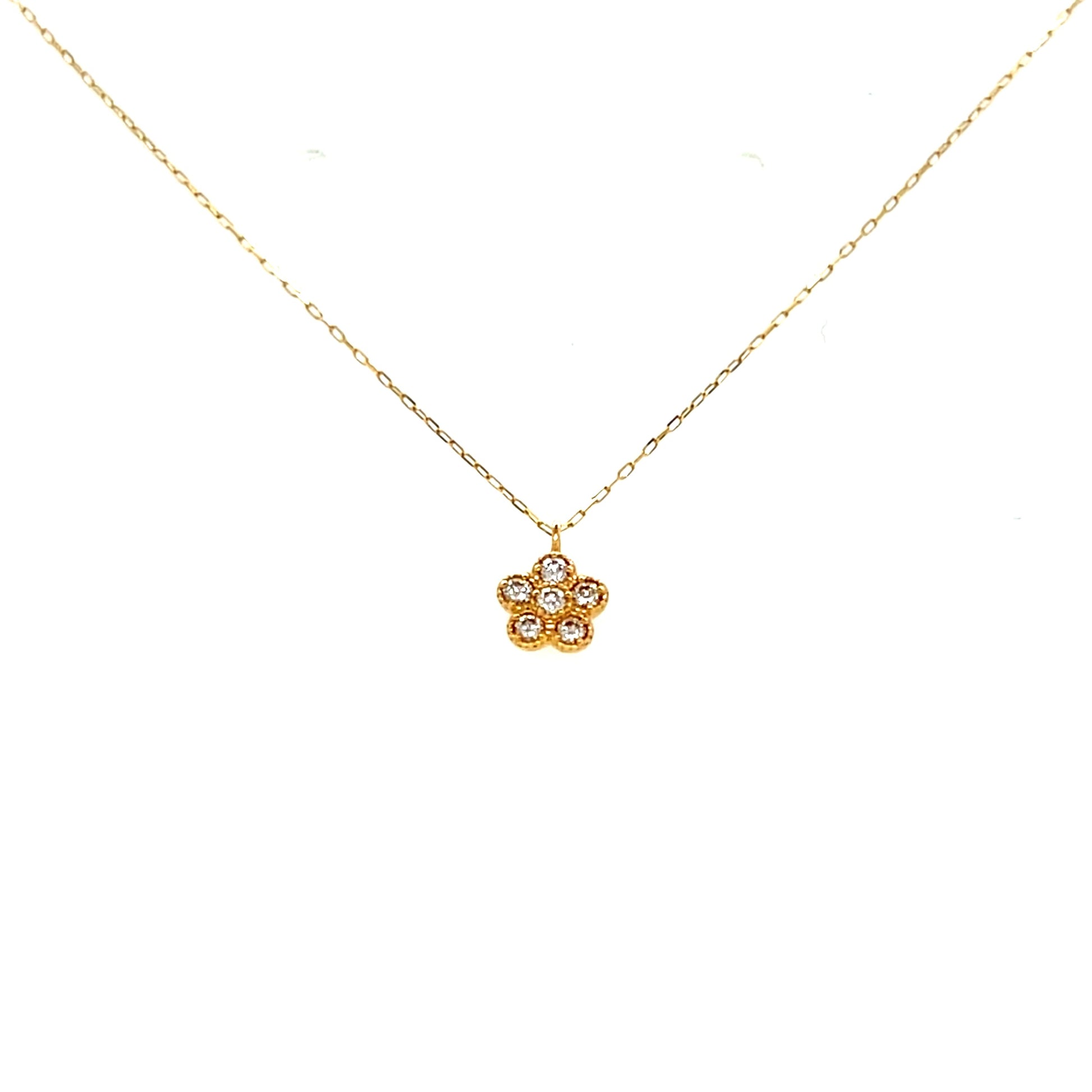 Gold necklace with a small diamond flower pendant on a white background