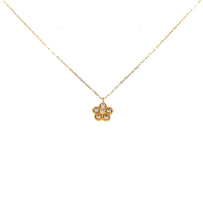 Gold necklace with a small diamond flower pendant on a white background