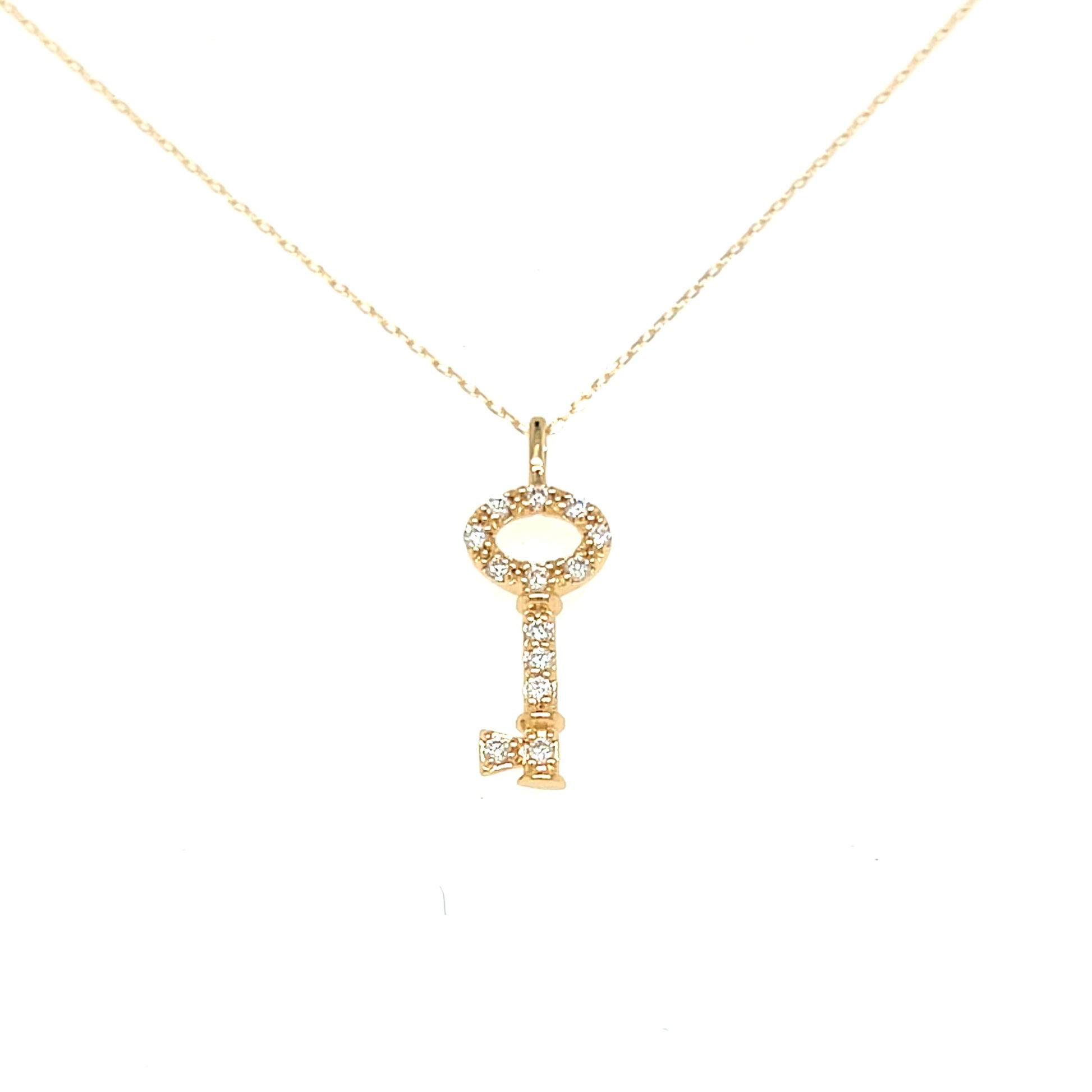 A gold key-shaped pendant necklace adorned with small clear stones, suspended from a delicate gold chain against a plain white background.