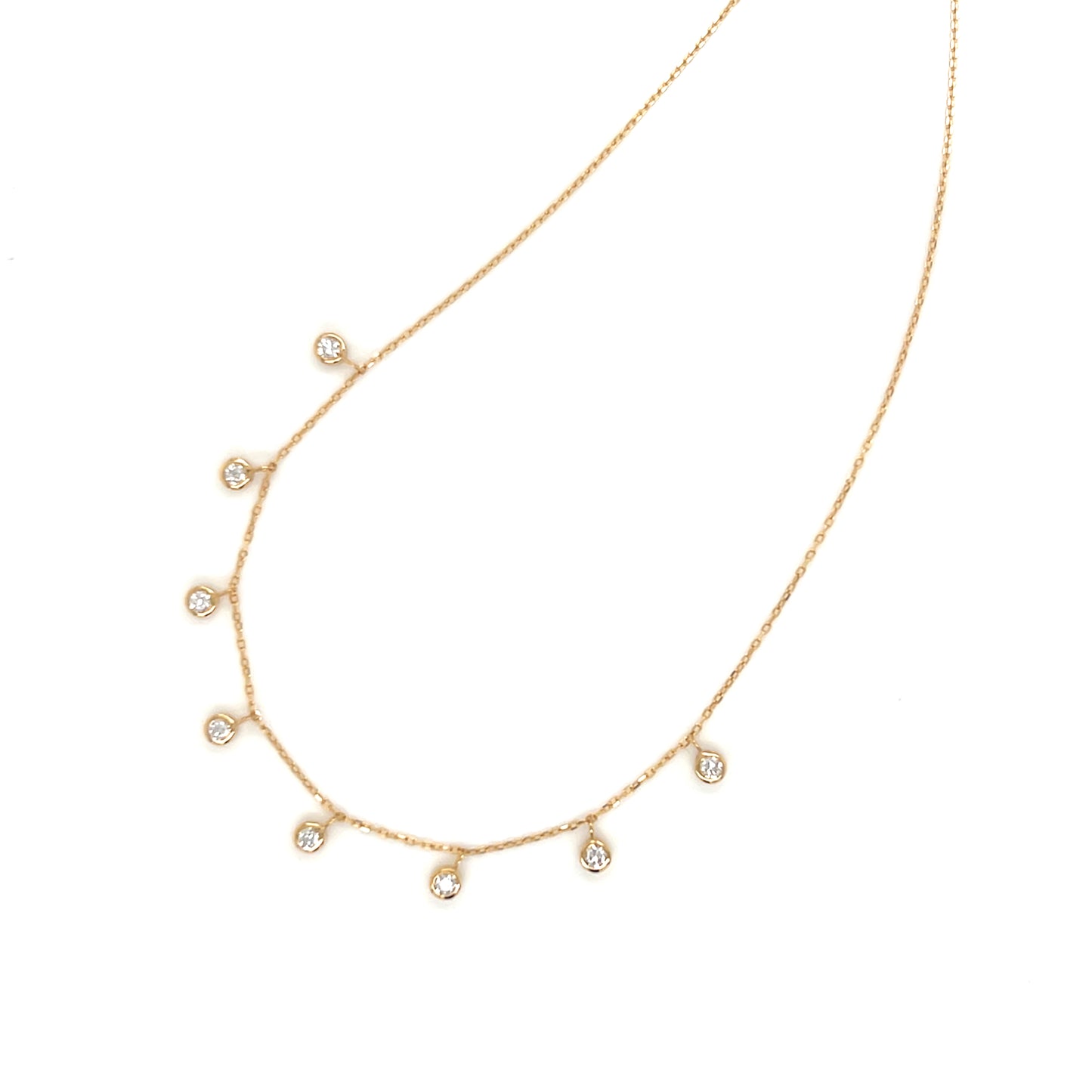 Gold necklace with small dangle bezel diamonds on a white background