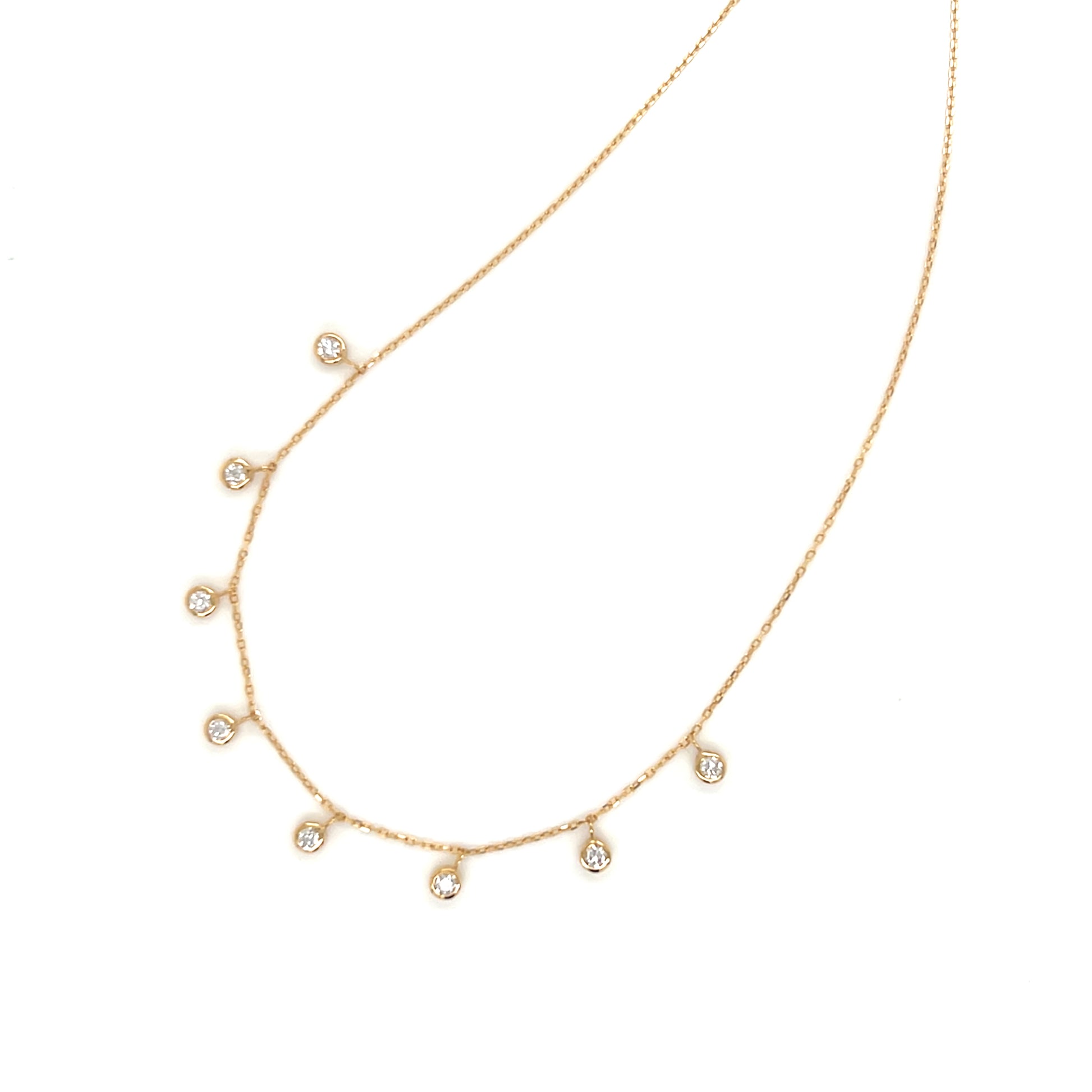Gold necklace with small dangle bezel diamonds on a white background