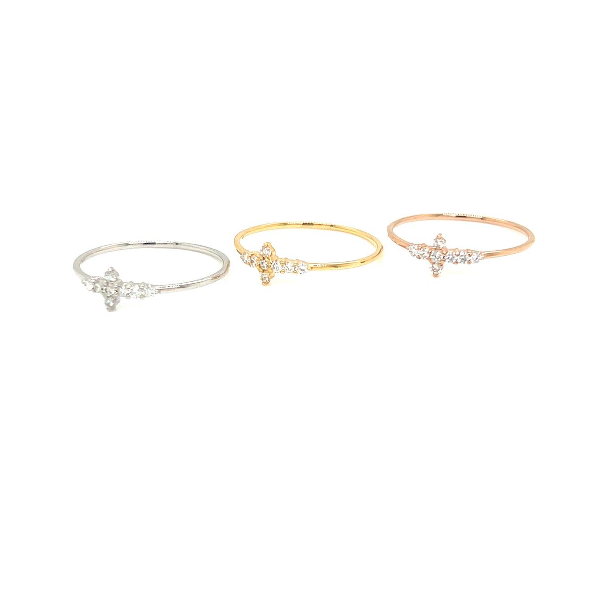 Three delicate open-band rings with small starburst crystal clusters in silver, yellow gold, and rose gold tones, arranged horizontally on a plain white background.