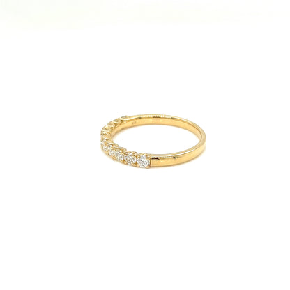 A yellow gold eternity ring featuring a row of small clear gemstones on the front, photographed on a seamless white background.