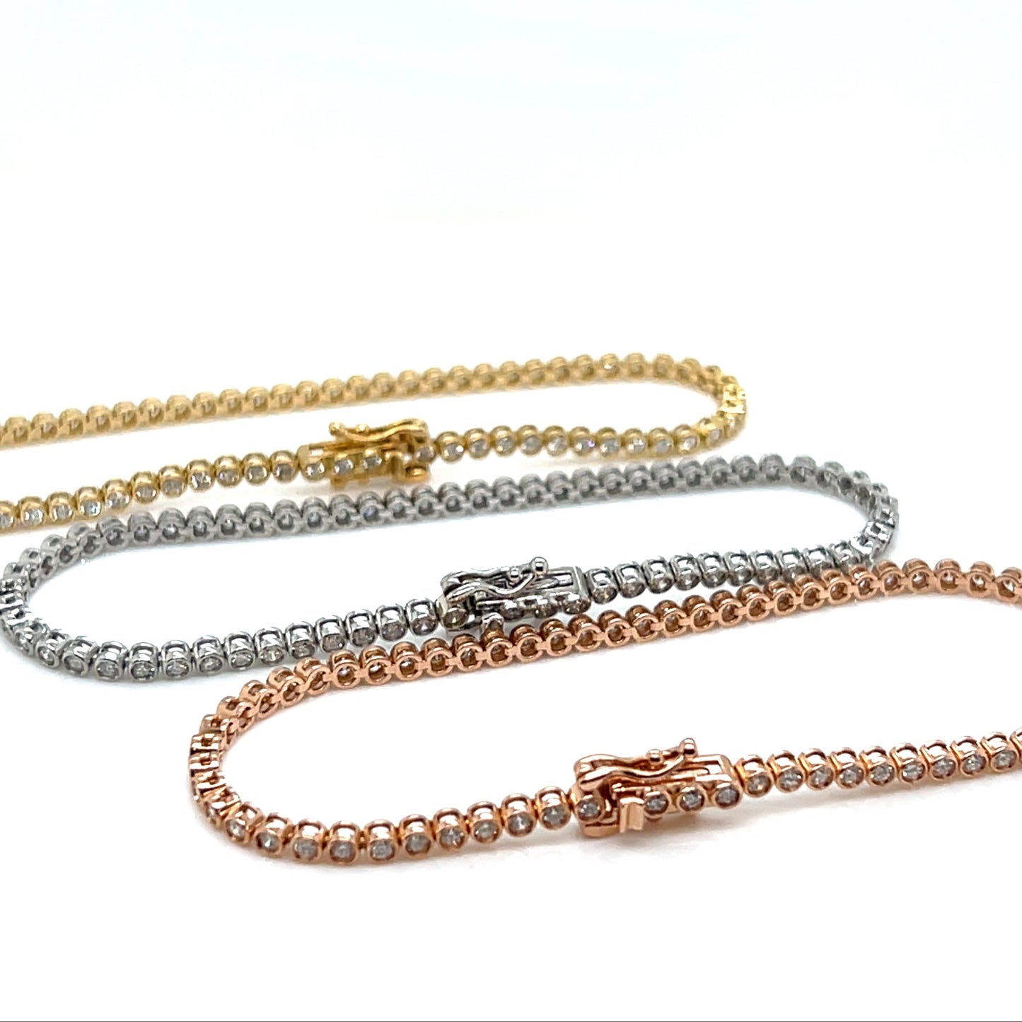 Three gold tennis bracelet of different colors on a white background
