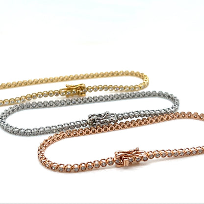 Three gold tennis bracelet of different colors on a white background