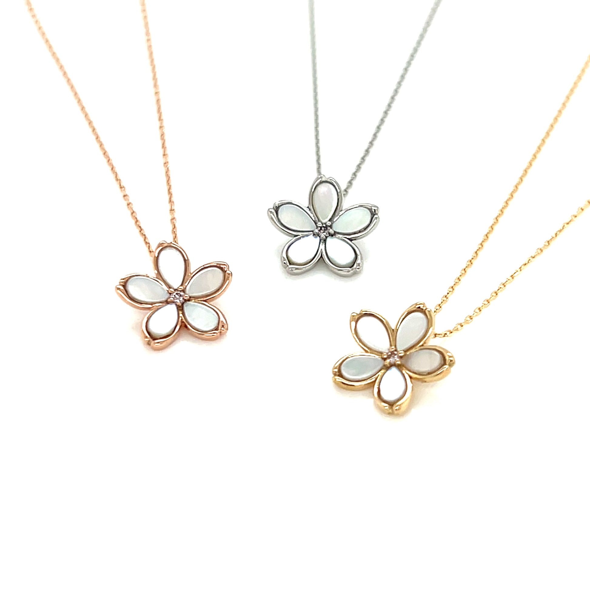 Three flower-shaped pendants on gold chains against a white background