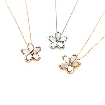 Three flower-shaped pendants on gold chains against a white background