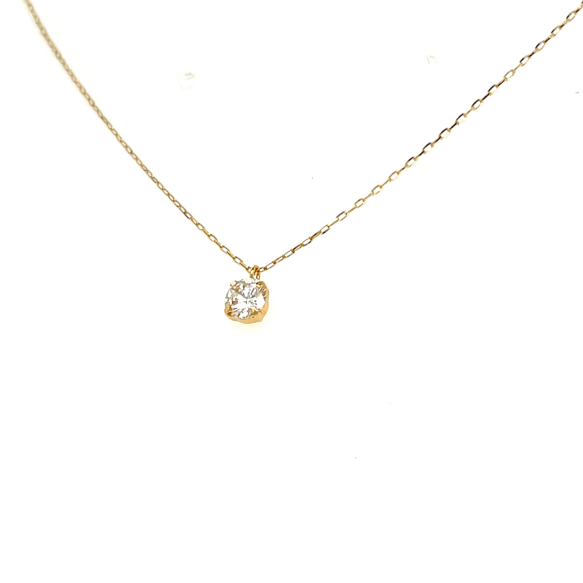 A delicate gold chain necklace with a small gold bezel-set pear-cut diamond pendant, shown against a plain white background.